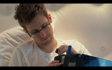 Snowden plugging an SD card in a laptop with a blue Tails USB stick